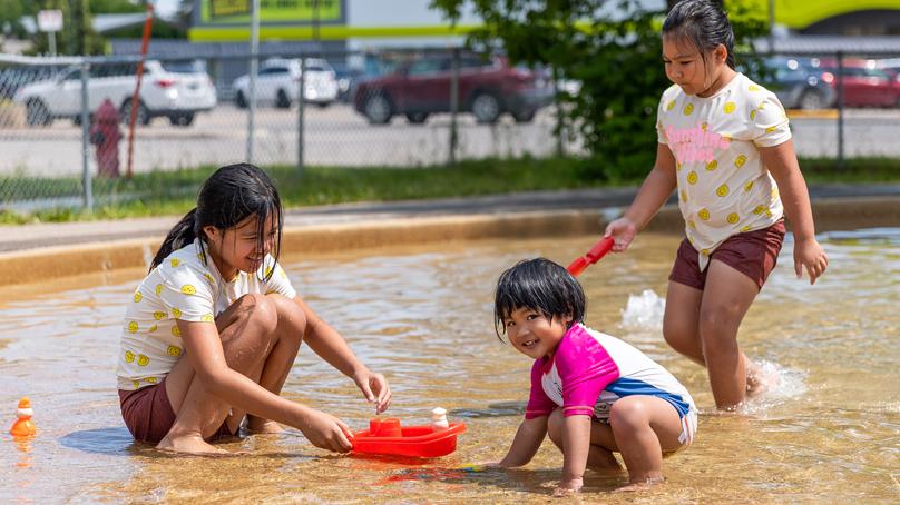 Three children playing in a wading pool in in the summer.