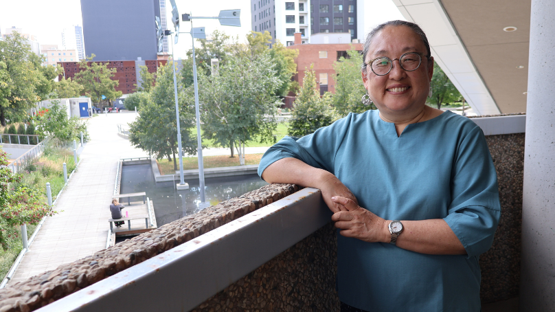 Sally Ito, 2026-2027 Writer-in-Residence, stands on the 2nd floor balcony of Millennium Library.