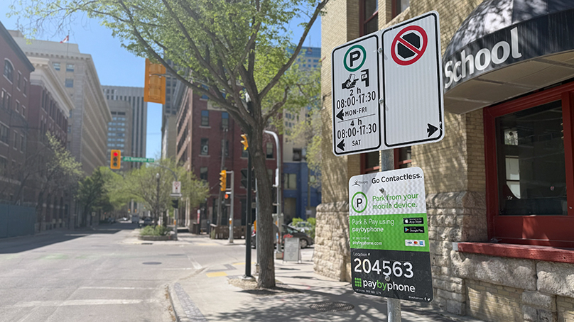 Parking signs on a pole along a sidewalk