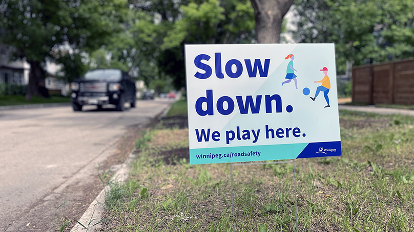 Lawn sign with message 'Slow down. We play here.'