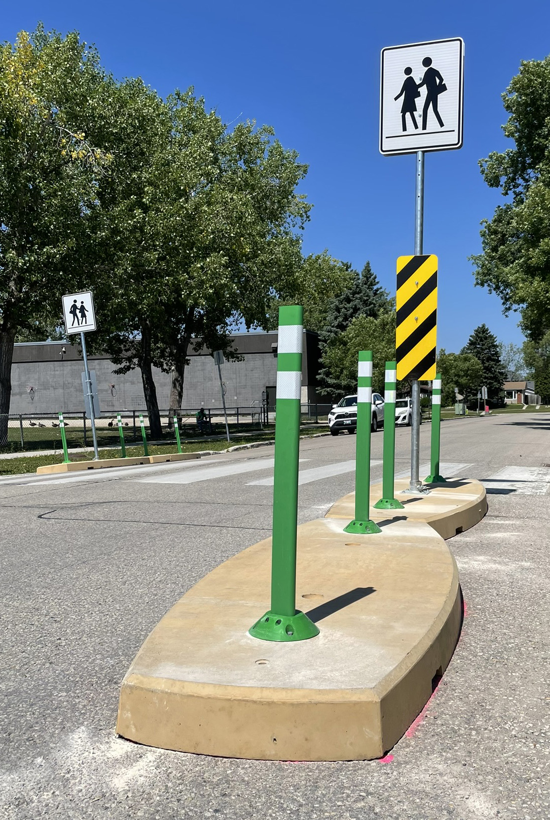 2000 pound concrete traffic calming curbs placed along the side of a road and next to a sidewalk.