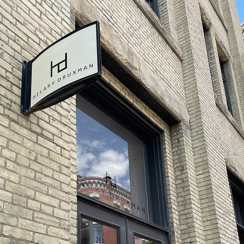 This projecting sign for Hilary Druxman Jewelry is a good example of a business identification sign on a Listed Historical Resource. It is appropriately sized, pedestrian oriented, and located next to the entrance of the business. Minimal penetrations have been made into the building to install the sign.