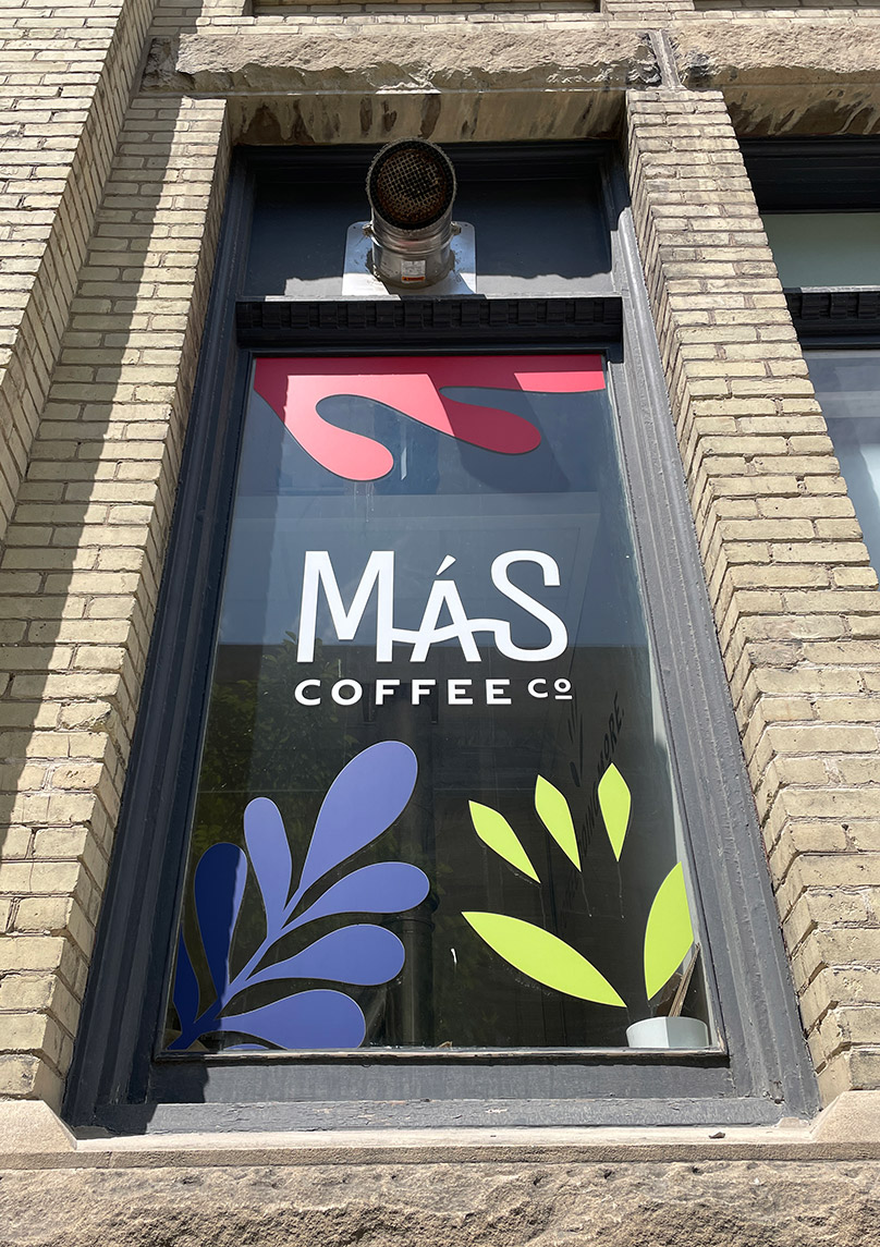The window decals at Mas Coffee Co. are a non-invasive method of adding signage to a heritage building.