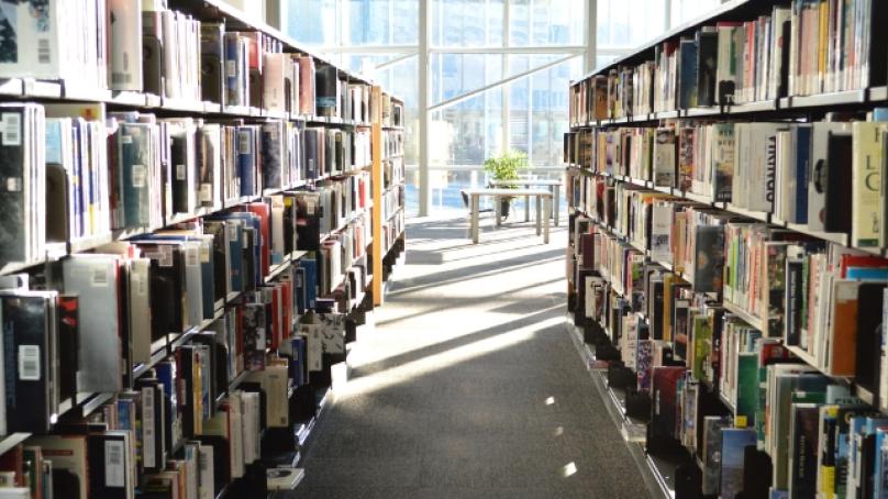Book stacks in the foreground with the windows of the fourth floor of Millennium Library in the background.
