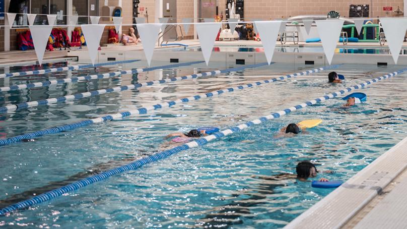 Swimmers with flutter boards in two lanes of pool.