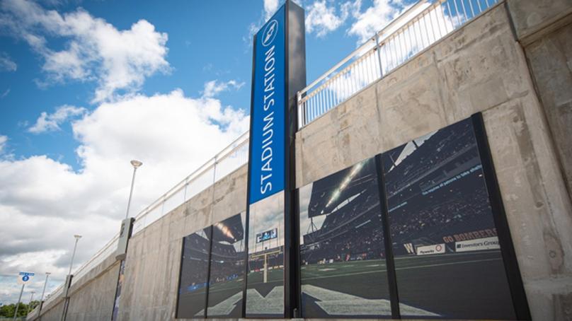 A Winnipeg Transit stop displays a poster of a Winnipeg Blue Bombers game