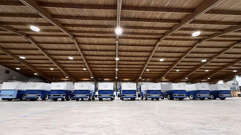 a line of Zambonis in side an empty arena with no ice