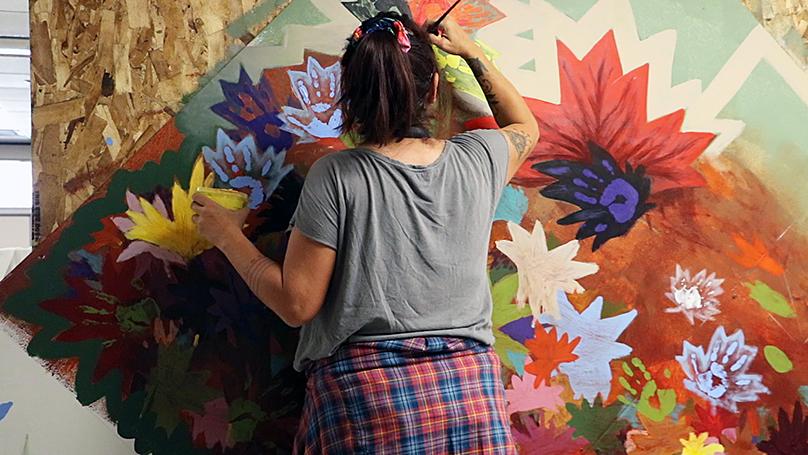 Jeannie White Bird works on the mural.