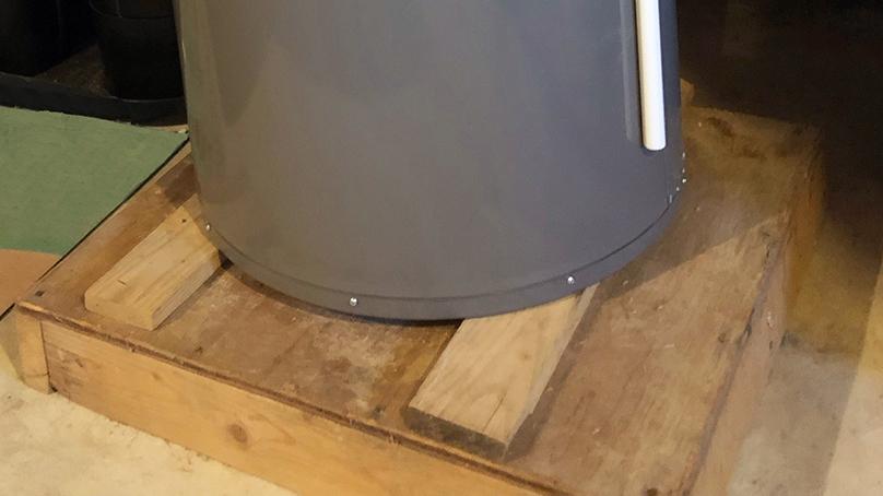 A hot water tank raised on pieces of wood.