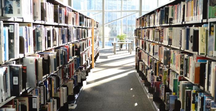 Book stacks in the foreground with the windows of the fourth floor of Millennium Library in the background.