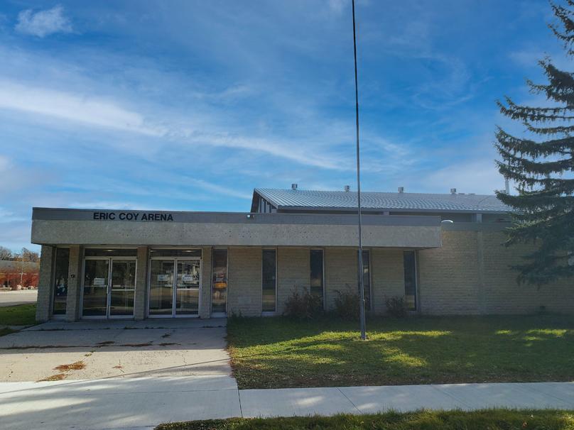 Glass doors mark the entrance of Eric Coy Arena on a partly cloudy fall day.