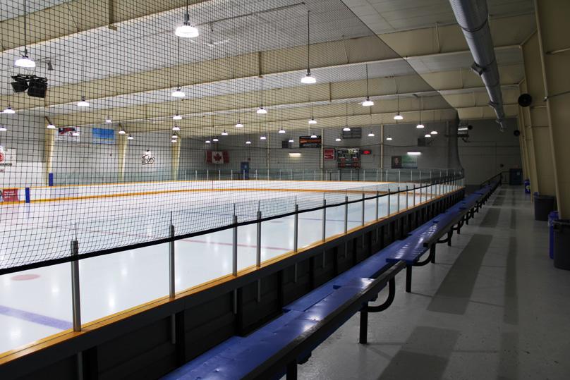 Lights gleam off of the Sam Southern Arena ice surface with blue benches in the seating area in the foreground.