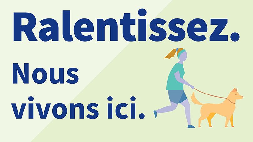 The other side of the bilingual lawn sign with a person walking a dog reads 'Ralentissez. Nous vivons ici.’