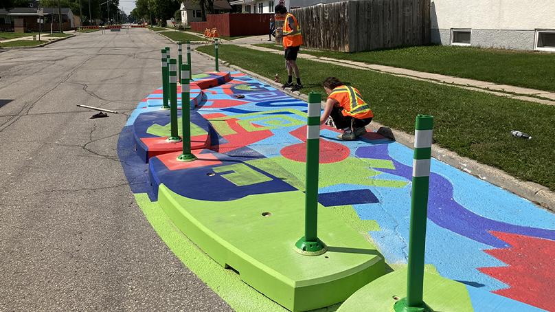 Crew members put finishing touches on the traffic calming curb mural at Watt Street and Hazel Dell Avenue.