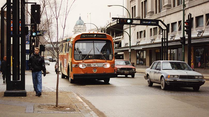 Bus No. 761 travels north on Vaughan St. past the Hudson's Bay store on the right. The Legislature is visible in the background. Taken in 1995.