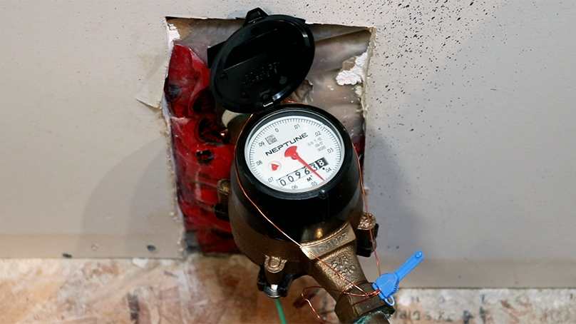A water meter with the lid open, showing the face of the water meter.